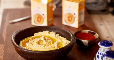 Hummus in Schüssel, Tetra Recart Verpackung im Hintergrund